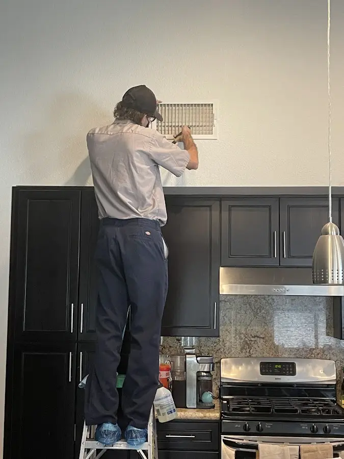 Technician inspecting an air vent during HVAC service in Coralville